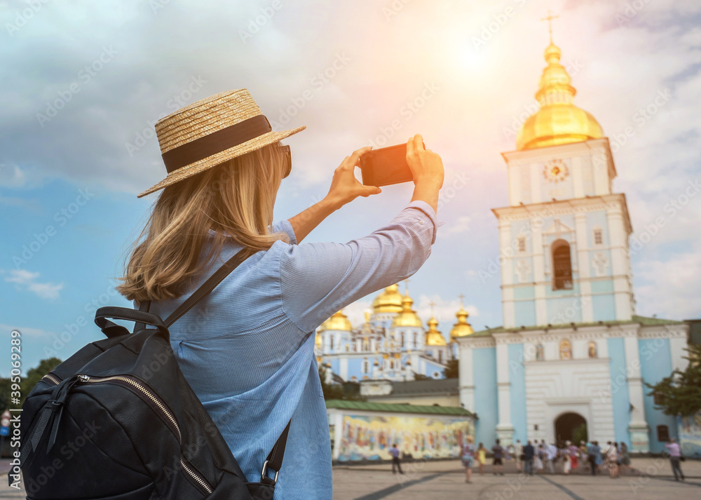 Woman traveler tourist using smartphone, taking photo of church Kiev, Ukraine in summer sunny day. Enjoying European, Famous popular touristic place in world.