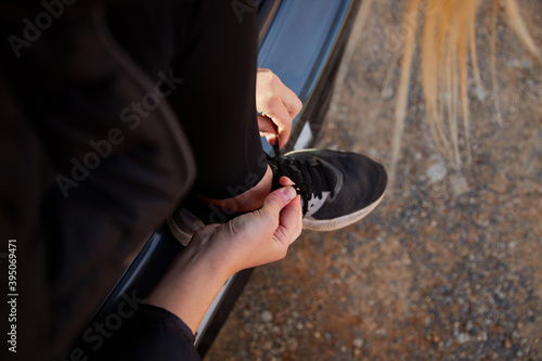 Close Up Of Woman Sitting In Open Tailgate Of Car Tying Shoes Before Hike In Countryside © Southworks