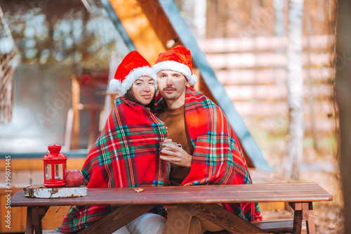 Young family in santa hat sitting on the wooden old table background of their house
