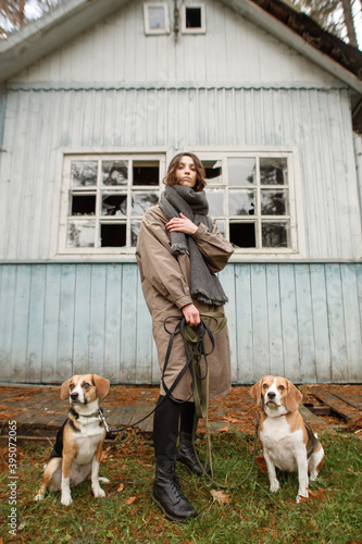 young stylish woman with two beagle dogs in the forest