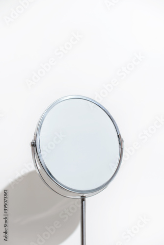 Round makeup mirror on a white background. Minimalism vertical photo.