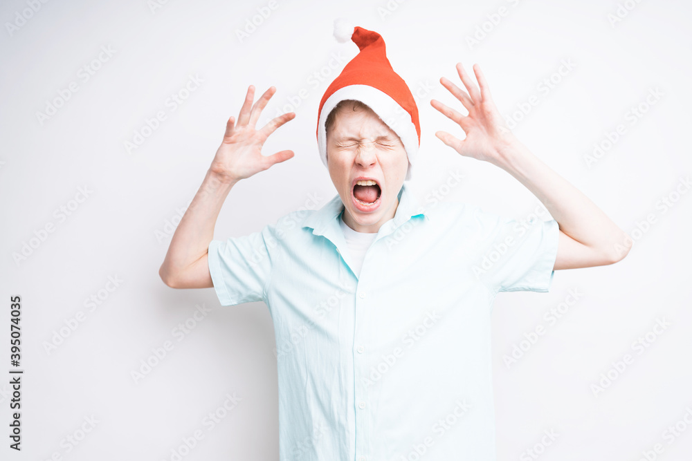 A caucasian boy on white background with a Santa Claus hat is screaming A caucasian boy on white background with a Santa Claus hat is screaming
