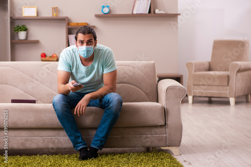 Young man watching tv at home during pandemic photo