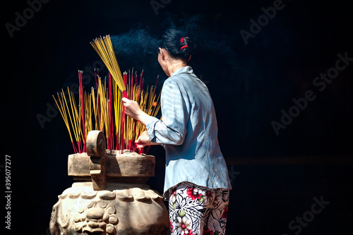 Fotografia The woman is burning incense in an ancient pagoda in Ho Chi Minh City