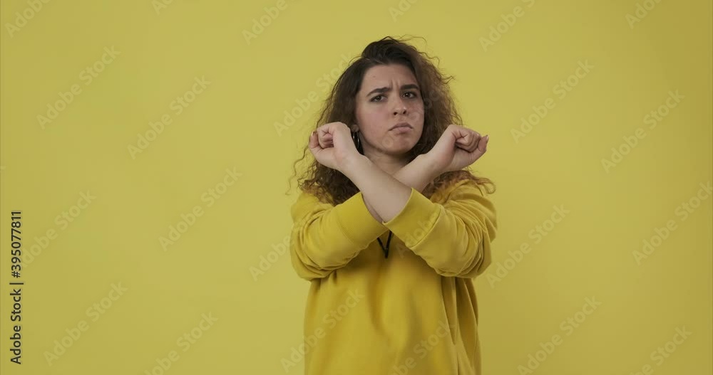 Woman crossing arms in denial over yellow background Woman crossing arms in denial over yellow background