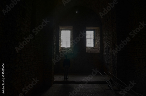 Woman in prison cell. Girl inside jail. Window in old prison cell. Medieval prison with iron bars. Security grids in Dungeon. Prisoner view. Rods on a locked gate in castle. Barred doors in dungeon  photo