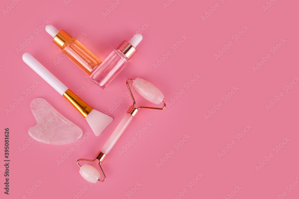 Jade face roller and Gua sha stone for facial massage. Home skin care anti-aging tools, face serum bottle, massage roller. Natural organic essential oil, skincare beauty product. Flat lay, top view. Jade face roller and Gua sha stone for facial massage. Home skin care anti-aging tools, face serum bottle, massage roller. Natural organic essential oil, skincare beauty product. Flat lay, top view.