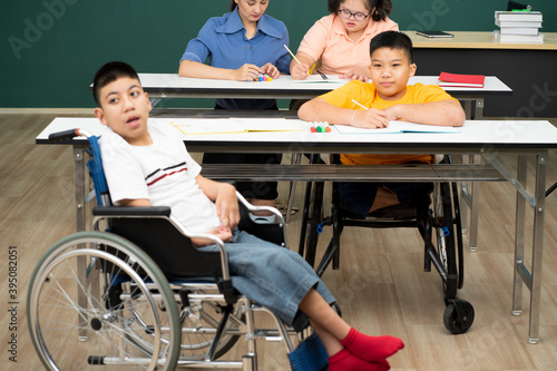 disability boy sitting on wheelchair in classroom special with teacher and AUtism kids education