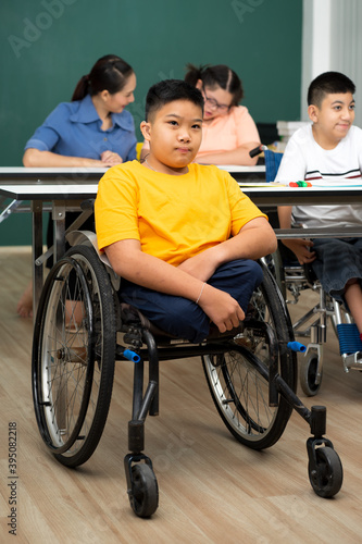 disability boy sitting on wheelchair in classroom special with teacher and AUtism kids education