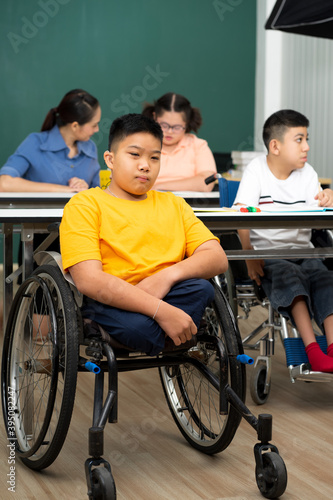 disability boy sitting on wheelchair in classroom special with teacher and AUtism kids education © ake