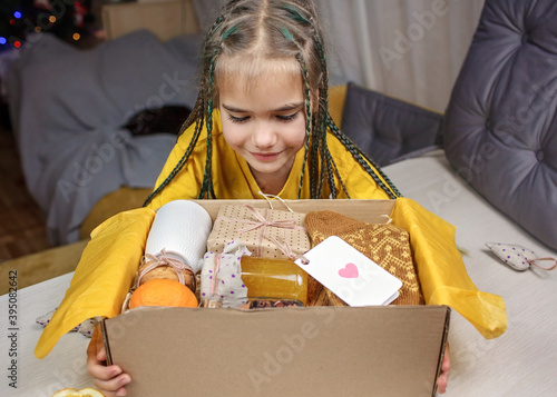Fotografija Girl packing care box with honey, cookies and knitted socks for grandmother duri