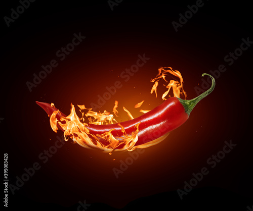 Canvas Print Red chili pepper close-up in a burning flame on a black background