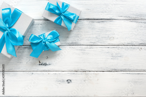 Gift boxes with blue bow on a white old wooden background. Top view, flat lay. Holiday and shopping concept.