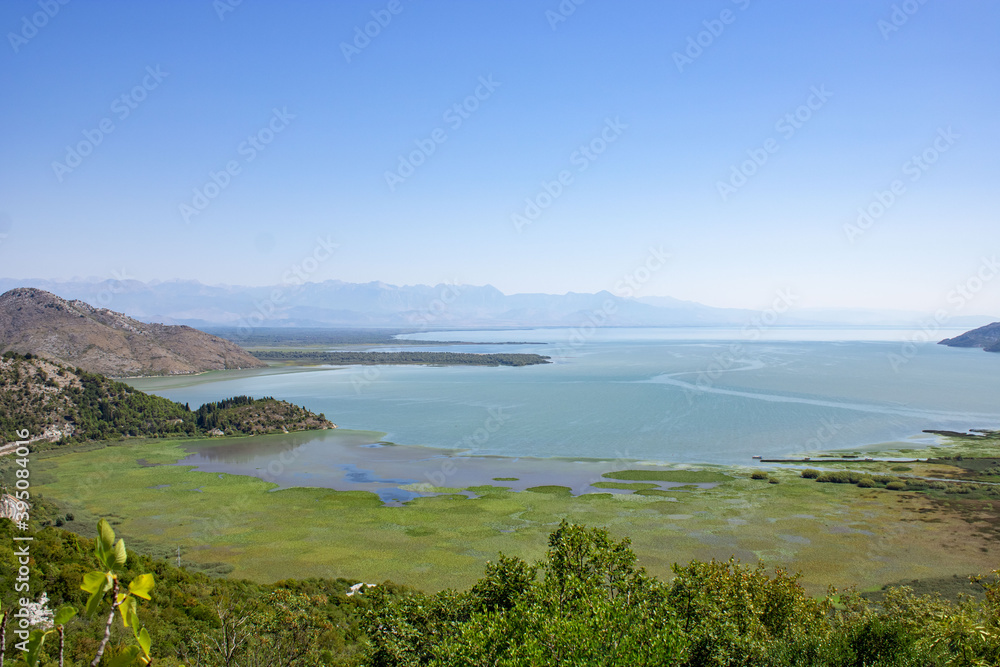 A beautiful view of the Skadar (Skoderskoe) lake among the mountains. Mountain landscape in the haze. Montenegro.