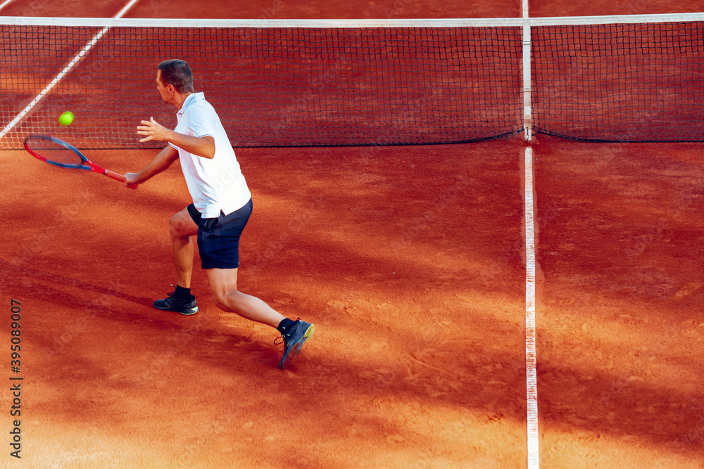 Back view of a man playing tennis on tennis court