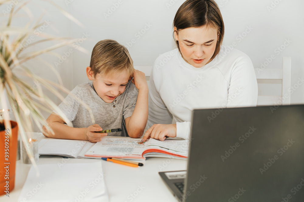Tutoring. Home schooling. Teacher and pupil. A woman and a blonde boy at the table. Tutoring. Home schooling. Teacher and pupil. A woman and a blonde boy at the table.