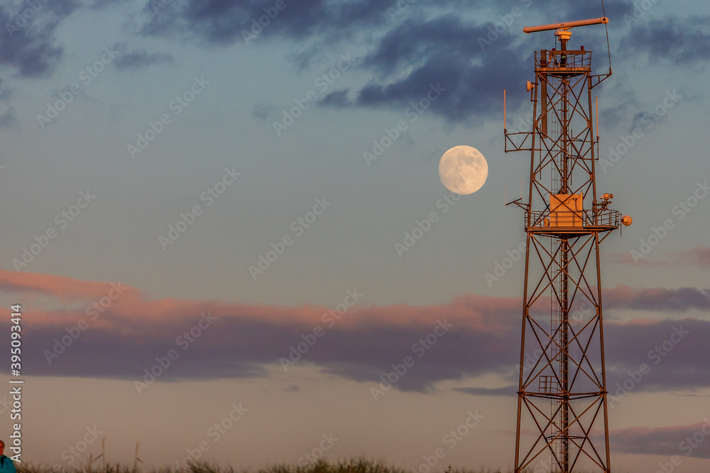 telecommunication antenna tower and moon at sunset time