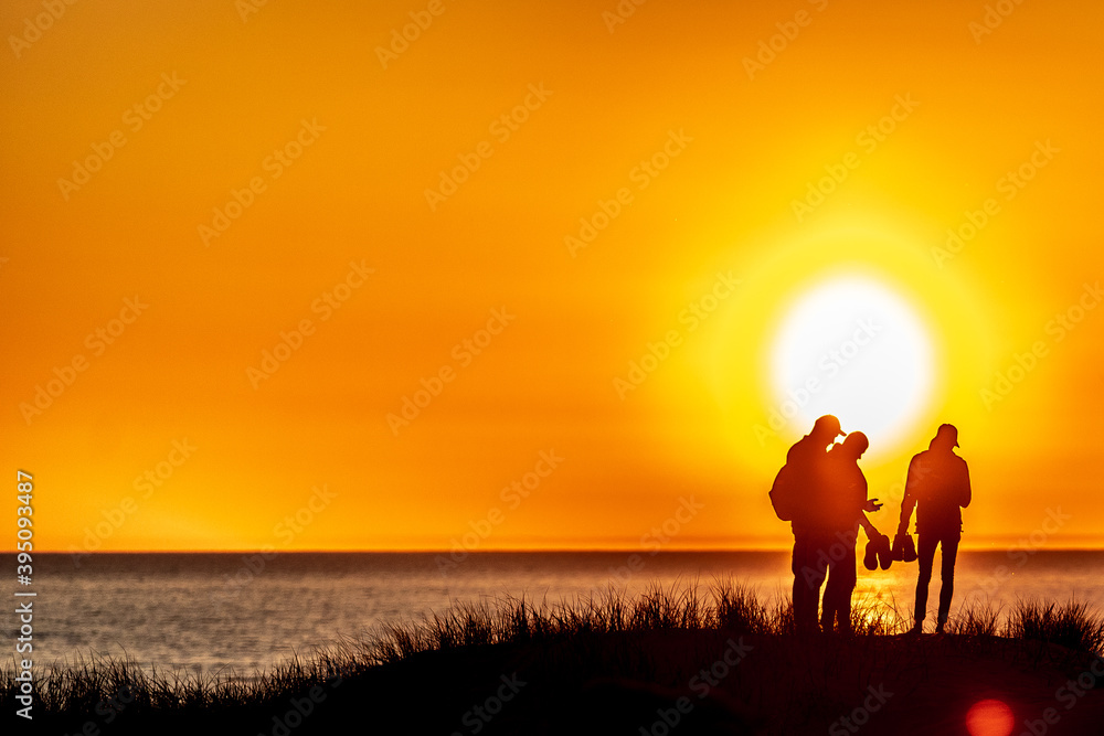 Silhouette of a group of four people standing at the hill on sunset
