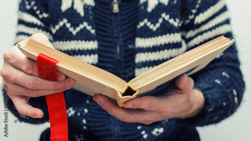 man holding an old book in his hands, with a ribbon between the pages