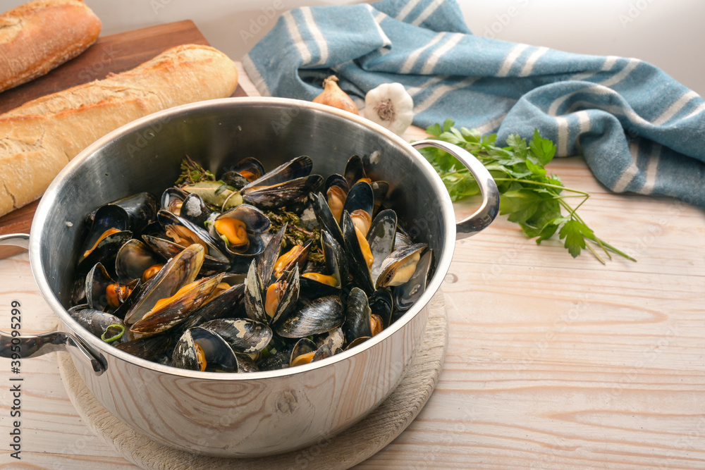 Freshly cooked mussels in a pot, bread, herbs and a blue towel on a wooden kitchen table, healthy seafood meal, copy space, selected focus, narrow depth of field Freshly cooked mussels in a pot, bread, herbs and a blue towel on a wooden kitchen table, healthy seafood meal, copy space, selected focus, narrow depth of field