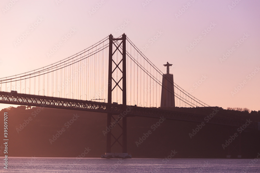 Fototapeta premium Ponte 25 de Abril Lisboa Lisbon Portugal bridge and Sanctuary of Christ the King, Santuário de Cristo Rei in the morning sunrise over Tagus river