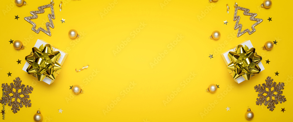 Fototapeta premium Gift boxes yellow. White gifts with golden ribbon, New Year balls and sparkling lights in Christmas composition on dark yellow background for greeting card. Xmas backdrop with space for text.