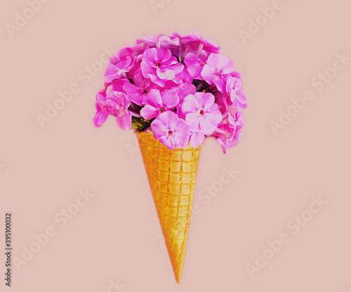 Close up of cone with pink flowers as ice cream over background