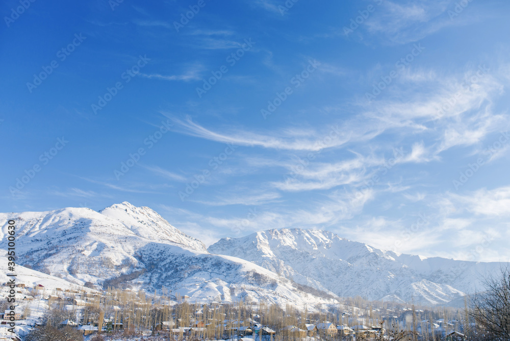 Beautiful mountain landscape in winter in Uzbekistan in the area of mount Chimgan. Cirrus clouds in a blue sky