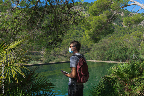 Young man with a bag on shoulder, medical safety mask and sunglasses. Halthcare outdoors concept. photo