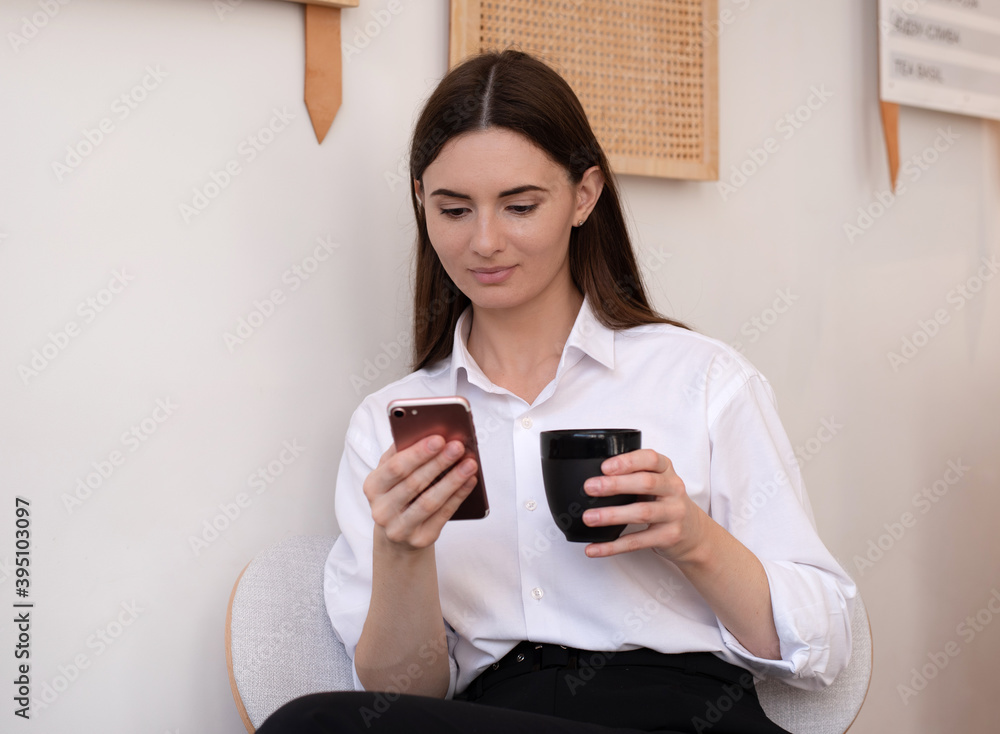 Young beautiful woman with a Cup of coffee in her hands. Bright interior of the cafe. Young beautiful woman with a Cup of coffee in her hands. Bright interior of the cafe.
