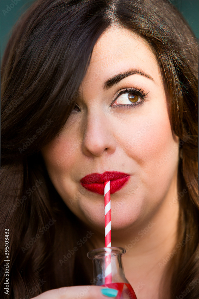portrait of brunette woman drinking from a bottle with straw portrait of brunette woman drinking from a bottle with straw