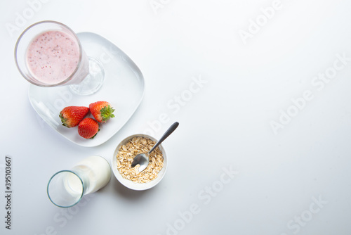 strawberry cereal cocktail for breakfast in a glass cup on a white plate with ingredients. shooting from top to bottom. flat composition. with free space for text, labels and logos
