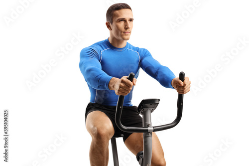 Young fit man in a blue sport top exercising on a stationary bike