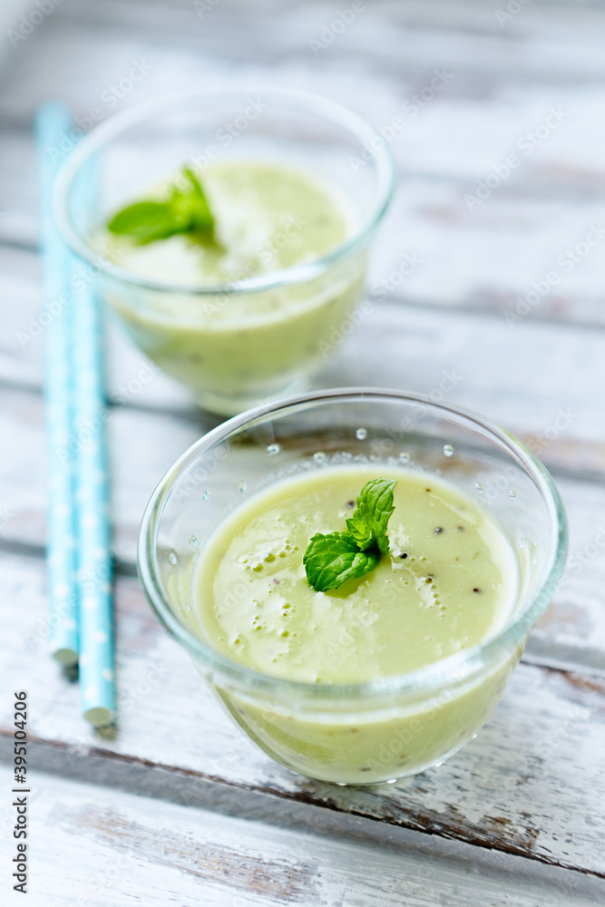 Green smoothie topped with chia seeds on bright wooden background. Close up. Green smoothie topped with chia seeds on bright wooden background. Close up.