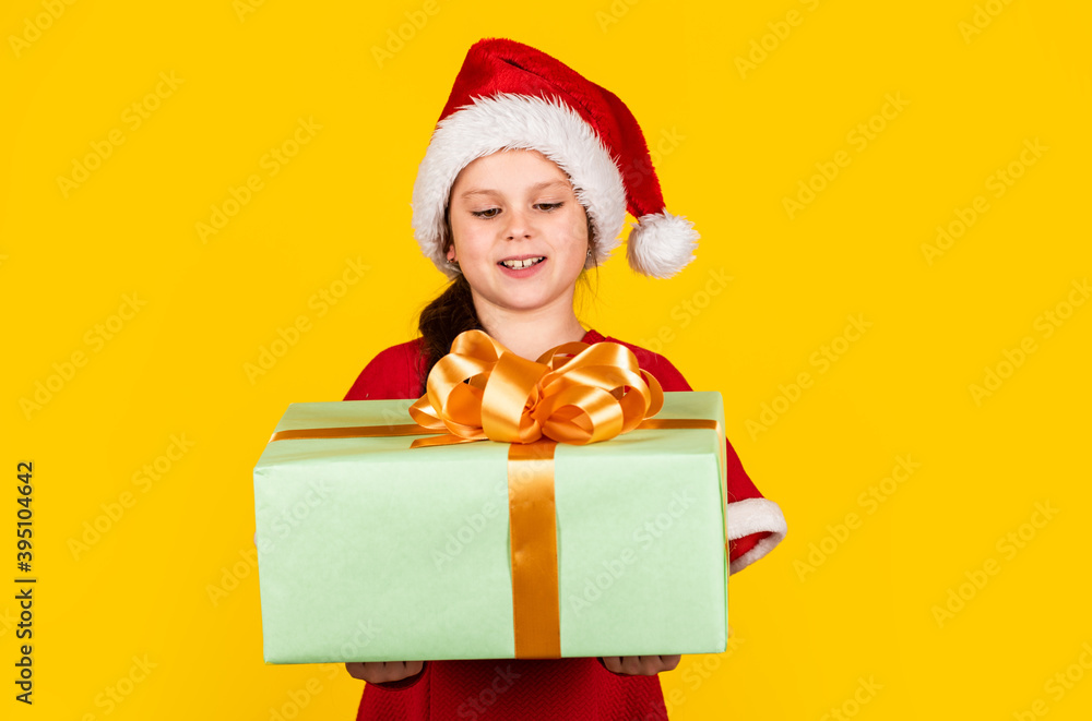 Kid hold present box yellow background. Merry Christmas and happy holidays. Dreams come true. Winter holidays. My happy day. Xmas gift shopping. Gift package. Small girl Santa hat hold gift box Kid hold present box yellow background. Merry Christmas and happy holidays. Dreams come true. Winter holidays. My happy day. Xmas gift shopping. Gift package. Small girl Santa hat hold gift box
