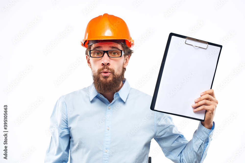 A man in an orange hard hat with documents Industrial activity work A man in an orange hard hat with documents Industrial activity work
