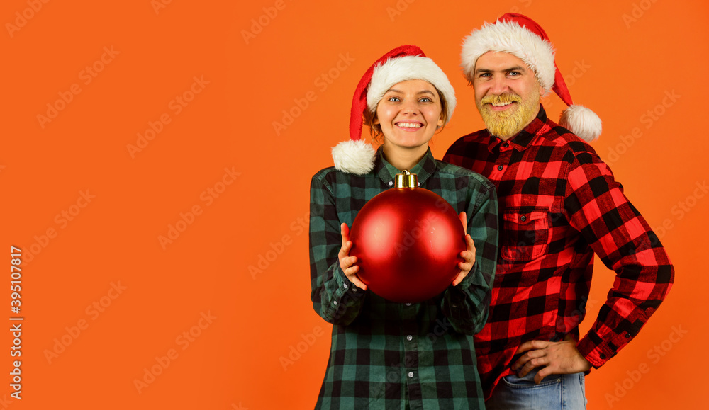 Fototapeta premium Entertainment ideas for adults. Santa team. Loving couple orange background. Christmas magical time. We love christmas. Couple in love enjoy christmas holiday celebration. Family wear santa hats