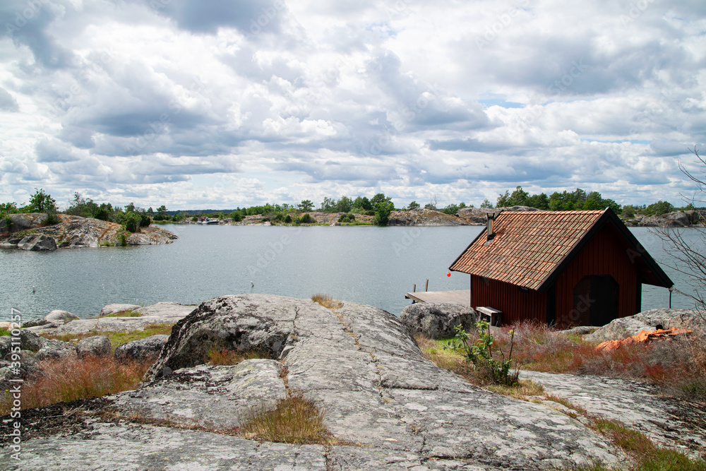 Small red wooden building next to the sea in the Swedish archipelago on a summer day. Idyllic vacation and travel destination in Sweden. Small red wooden building next to the sea in the Swedish archipelago on a summer day. Idyllic vacation and travel destination in Sweden.