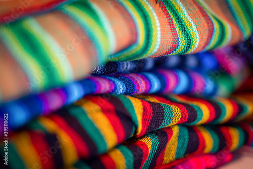 Wool fabric rolls of assorted colors laying one on top of each other, in a local store, for sale. Made in Ecuador.