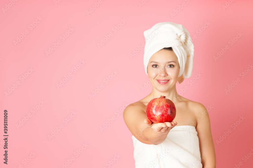 mock up, a ripe pomegranate on the palm of a young woman in defocus on a pink background mock up, a ripe pomegranate on the palm of a young woman in defocus on a pink background