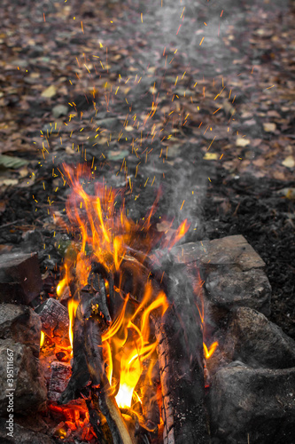 Bright flames. Fire sparks. Burning firewood. Crackling logs on fire. Smouldering coals. Christmas background. The heat and warmth of an open fire. Risk of fire. Dangerous behavior with fire.