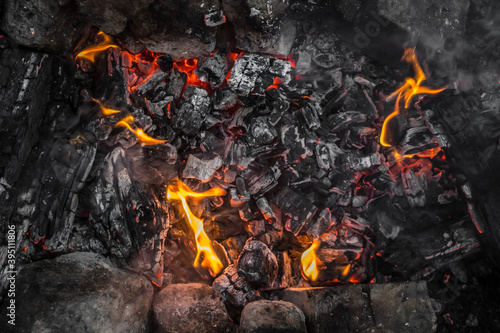 Bright flames. Fire sparks. Burning firewood. Crackling logs on fire. Smouldering coals. Christmas background. The heat and warmth of an open fire. Risk of fire. Dangerous behavior with fire.