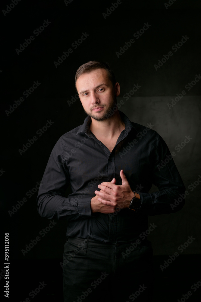 Studio portrait of a young caucasian man in a black blazer, looking at the camera, standing against plain studio background Studio portrait of a young caucasian man in a black blazer, looking at the camera, standing against plain studio background