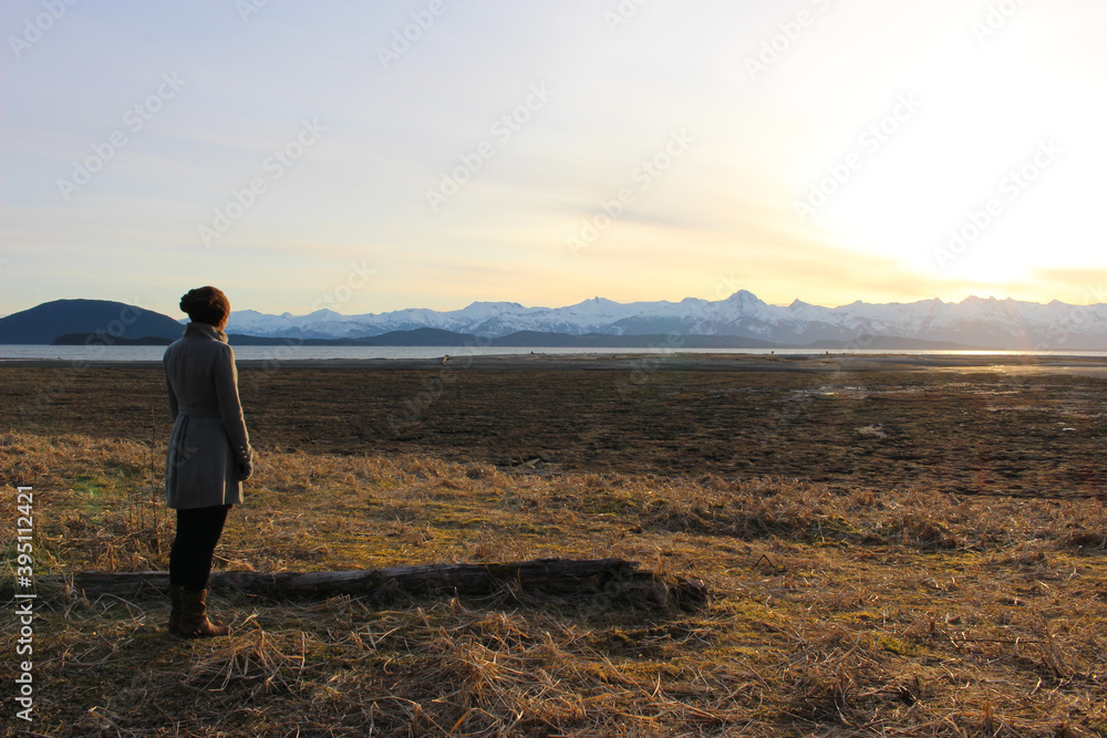 Young woman gazing off to the Chilkat mountain range in southeast Alaska at sunset Young woman gazing off to the Chilkat mountain range in southeast Alaska at sunset