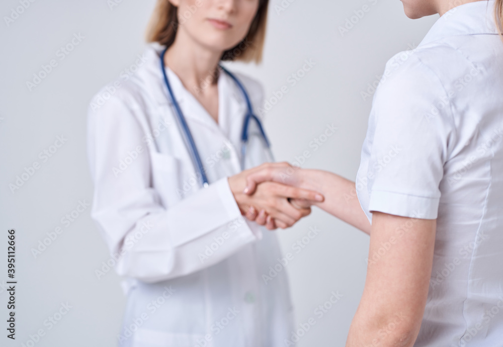 Doctor and patient shake hands with each other on a light background cropped view Doctor and patient shake hands with each other on a light background cropped view