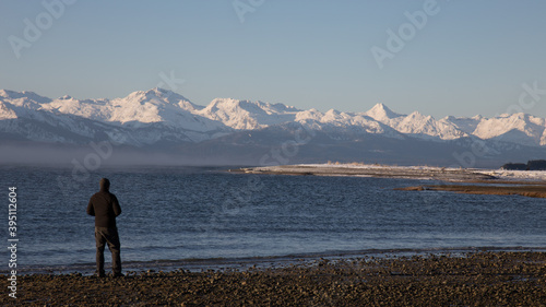 Man Standing on Eagle Beach Looking out over Lynn Canal to the Magnificent Chilkat Mountain Range in Southeast Alaska near Juneau, Alaska