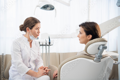A doctor talking to the patient in her dental office.