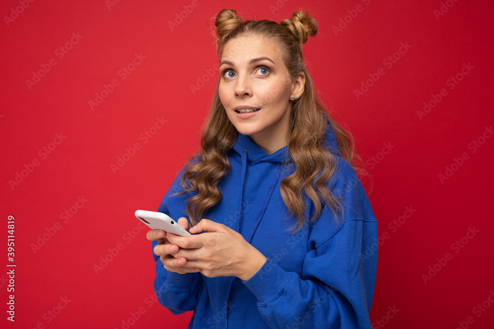 Naklejka premium Image of a thinking dreaming young beautiful woman posing isolated over red wall background using mobile phone.
