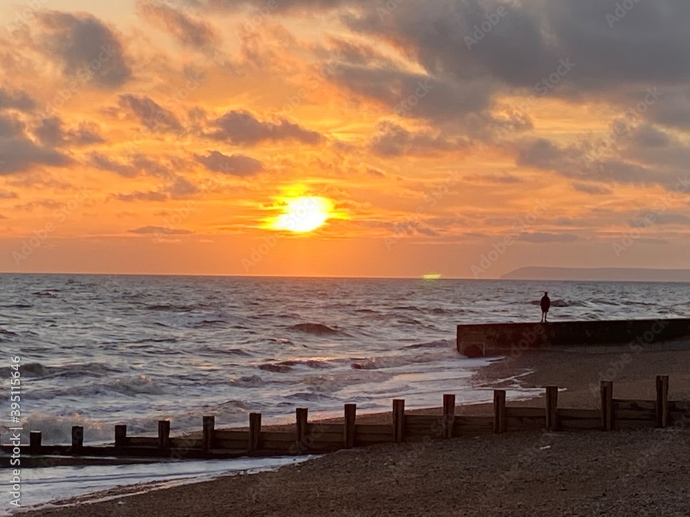 Hastings beach waves and seafront at sunset one man silhouette on concrete pier