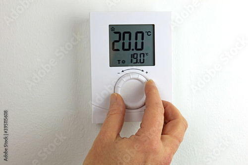 hand with thermometer controlling a homes heating. photo